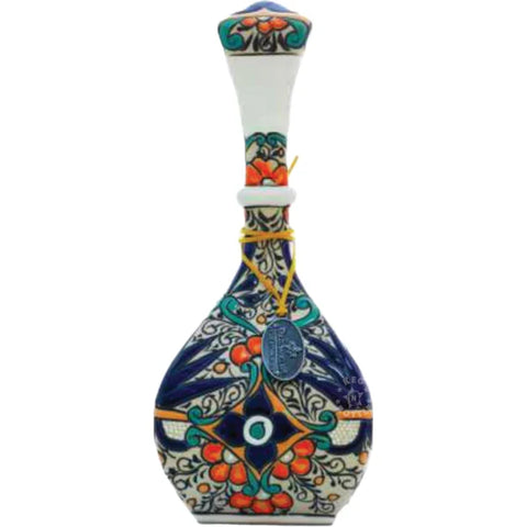 A colorful ceramic decanter with a stopper, decorated with floral and animal patterns, containing clear tequila with gold and copper sparkles.
