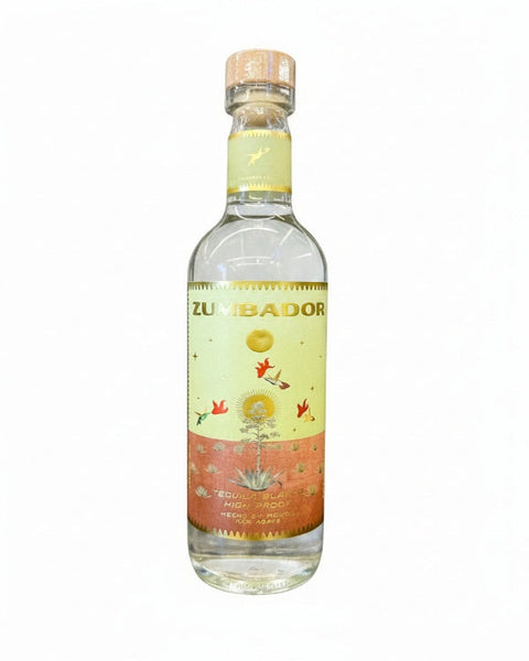 A bottle of Zumbador tequila on a plain white background. The clear glass bottle features a light yellow and orange label with illustrations of birds, a sun, and an agave plant, topped with a cork.